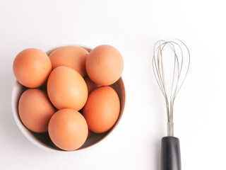 Egg beater with chicken eggs in a bowl isolated on white background.