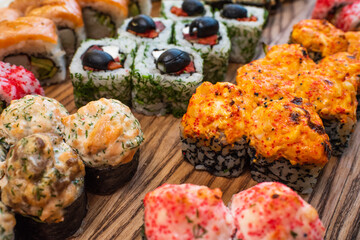 Different types of delicious and juicy sushi and rolls on a wooden board