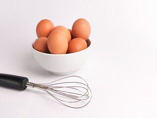 Egg beater with chicken eggs in a bowl isolated on white background.