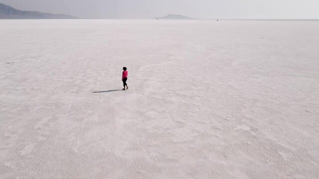 Aerial shot of an Asian woman hiking across the Bonneville Salt Flats flats in Utah