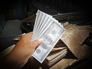 Selective focus photo with noise effect of man hand giving money like a bribe or tips.Holding dollar bank notes.