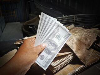 Selective focus photo with noise effect of man hand giving money like a bribe or tips.Holding dollar bank notes.