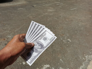 Selective focus photo with noise effect of man hand giving money like a bribe or tips.Holding dollar bank notes.