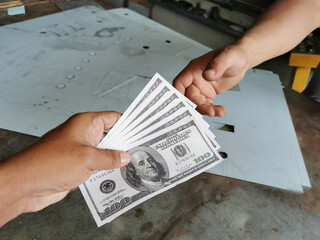 Selective focus photo with noise effect of man hand giving money like a bribe or tips.Holding dollar bank notes.