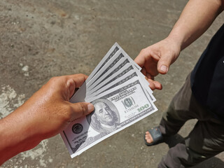 Selective focus photo with noise effect of man hand giving money like a bribe or tips.Holding dollar bank notes.