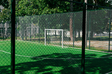 Soccer field behind the iron fence. School soccer stadium