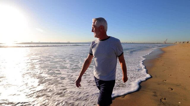 64 year old man walking at the beach near sunset.