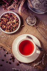 Cup of fruit tea with dried tea leaves in vintage look