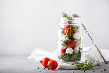 salad of mozzarella, cherry tomatoes and arugula in a glass mug