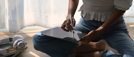 Close up view of woman artist illustrator drawing on digital tablet with stylus pen while sitting...