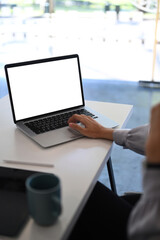 Cropped shot of young female sitting in modern office and using laptop searching information.