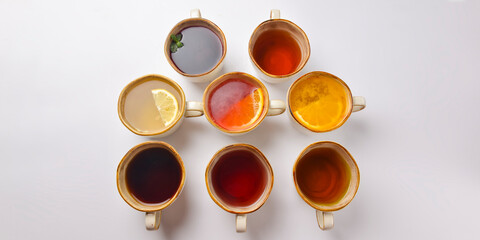White tea, green tea, black tea, fruit and berry tea in ceramic cups. Many cups over white background.