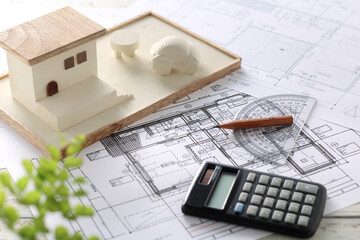 木でできた家の模型とマイホームの設計図のイメージ