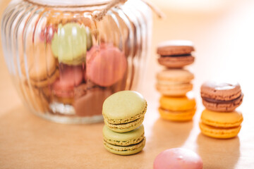 Macaroons of different colors in a glass container. Stacked macaroons