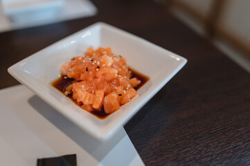 Close-up plate of salmon tartar with soy sauce in a sushi restaurant. Japanese healthy food concept.