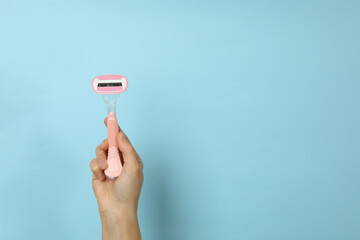 Female hand hold razor on blue background, space for text