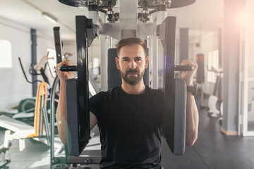 Man working hard at the gym. Pectoral muscles exercises with training weight machine station in gym.Health and Sport Concept.