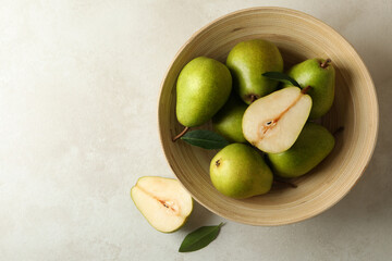 Bowl with green pears on white textured background