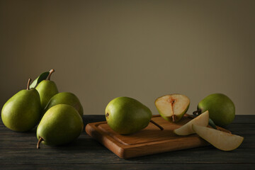 Board with fresh green pears on wooden background