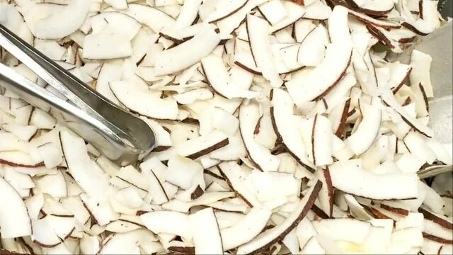 Roasted baked toasted natural thin sliced coconut chips. Background texture with white chopped coconut dried slices. HD