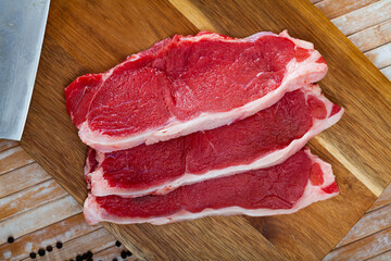 Pieces of beef with peas of bitter pepper on cutting board