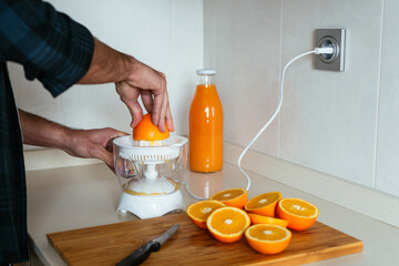 Side view of young man making orange juice at kitchen