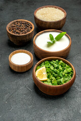 bottom view wooden bowls with rice natural yogurt parsley black pepper salt on dark background