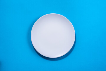 White plate on blue background. Selective focus. Shot from above