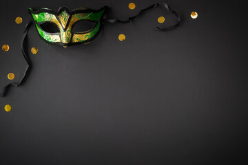 Mardi gras background on black with mask, golden glitters and copy space