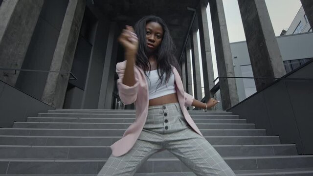 Young Black Girl Dancing Modern Dance On The Stairs. She Is In Business Clothes With High Heels.