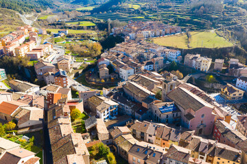Fototapeta premium Scenic aerial view of small Spanish town of La Pobla de Lillet at foot of Pyrenees mountains on sunny fall day, Catalonia