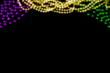 Mardi gras blurry bokeh purple, yellow, green beads background on black, overlay