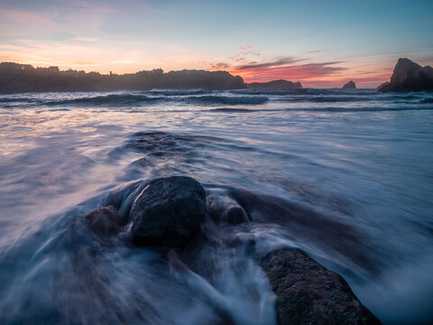 Beautiful landscape of Portio beach at sunset in Liencres, Cantabria. Waves crashing against rocks.