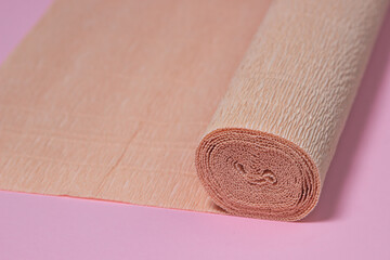 Colored corrugated paper. Roll of beige corrugated paper on a pink background. paper product
