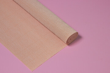 Colored corrugated paper. Roll of beige corrugated paper on a pink background. paper product