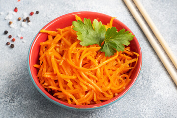 Raw grated spicy carrot salad in bowl. Korean carrot with spices and sauce.
