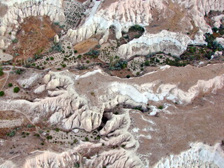 Fototapeta premium Panorama of the picturesque snow-white sharp-topped volcanic rocks of Cappadocia from the height of a balloon flight in dim light before sunrise.