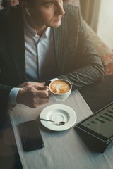 A young and attractive man uses his tablet while drinking coffe in an indoor restaurant