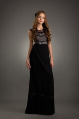 Fototapeta premium beautiful girl in a black dress posing in the studio on a gray background