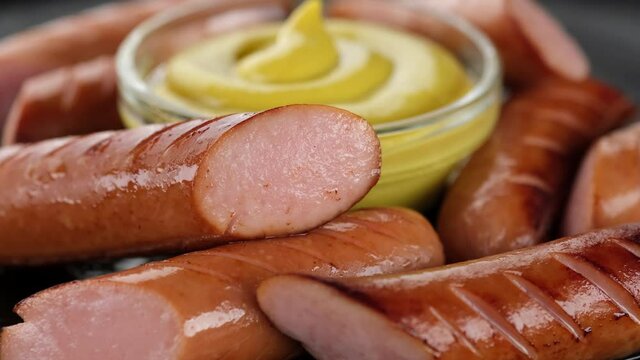 grilled sausages and mustard closeup on black plate