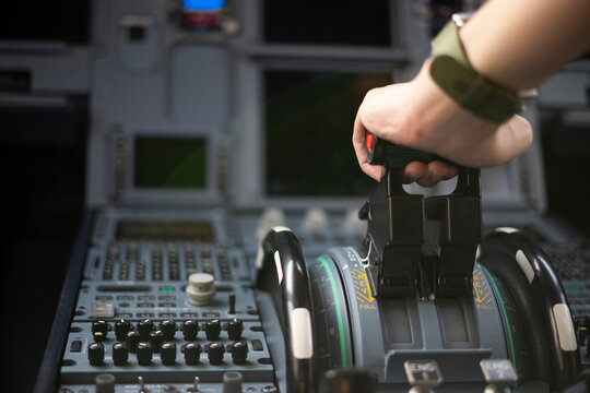 Cropped hands of pilot flying a commercial airplane, cockpit view close up of hands. Captain hand accelerating on the throttle in commercial airplane