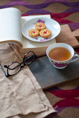 a cup of tea with a book and cake as decor