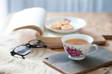 Fototapeta na wymiar a cup of tea with a book and cake as decor