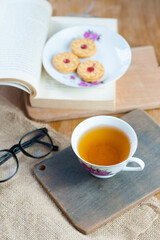 Obraz na płótnie Canvas a cup of tea with a book and cake as decor