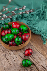 Easter colored eggs. Quail egg of green and red color on a wooden background. Willow branch. Happy Easter greeting card. Place for your text. Food on the background.