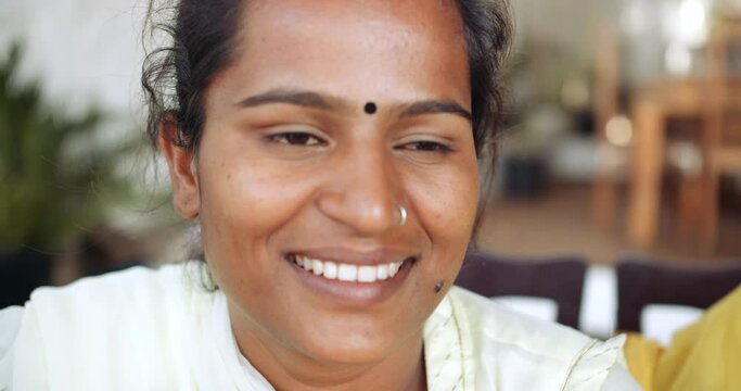 Slow-motion extreme close-up portraits of a young Indian woman in traditional clothes smiling looking at camera and speaking to someone off camera