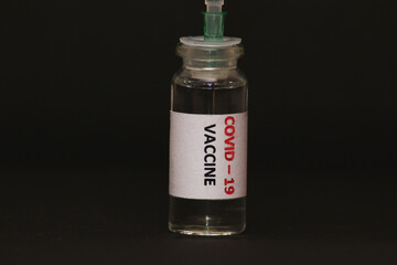 The concept of combating the coronavirus Covid-19. On a black background, a jar with a vaccine and a syringe.