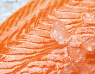 Fresh raw salmon fish steak with spices on ice over dark stone background. Creative layout made of fish, macro
