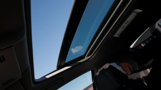Caucasian Scandinavian hands opening hatch sun glass roof window revealing blue cloudy sky letting out hot air wind blowing breeze on road trip vacation taking fresh breath air hot sweaty 2021 summer