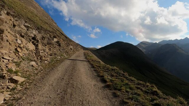 Mountain road with an offroad without asphalt. Mountains, natural road and trees are in the picture